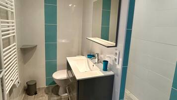 A modern bathroom with a white sink, a mirror, and a toilet.