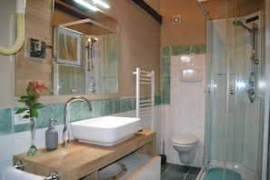 A bathroom with a white sink, mirror, and shower. - OASI LIGNANA Apartments (PESCIA)