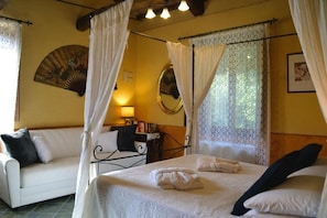A bedroom with a bed, a bedside table, a lamp, a mirror, and a fan. - OASI LIGNANA Apartments (PESCIA)