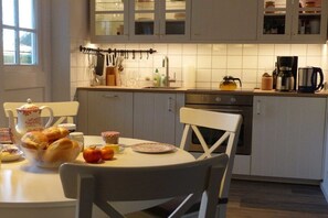 Een keuken met een ontbijttafel, compleet met brood, fruit en een theepot.