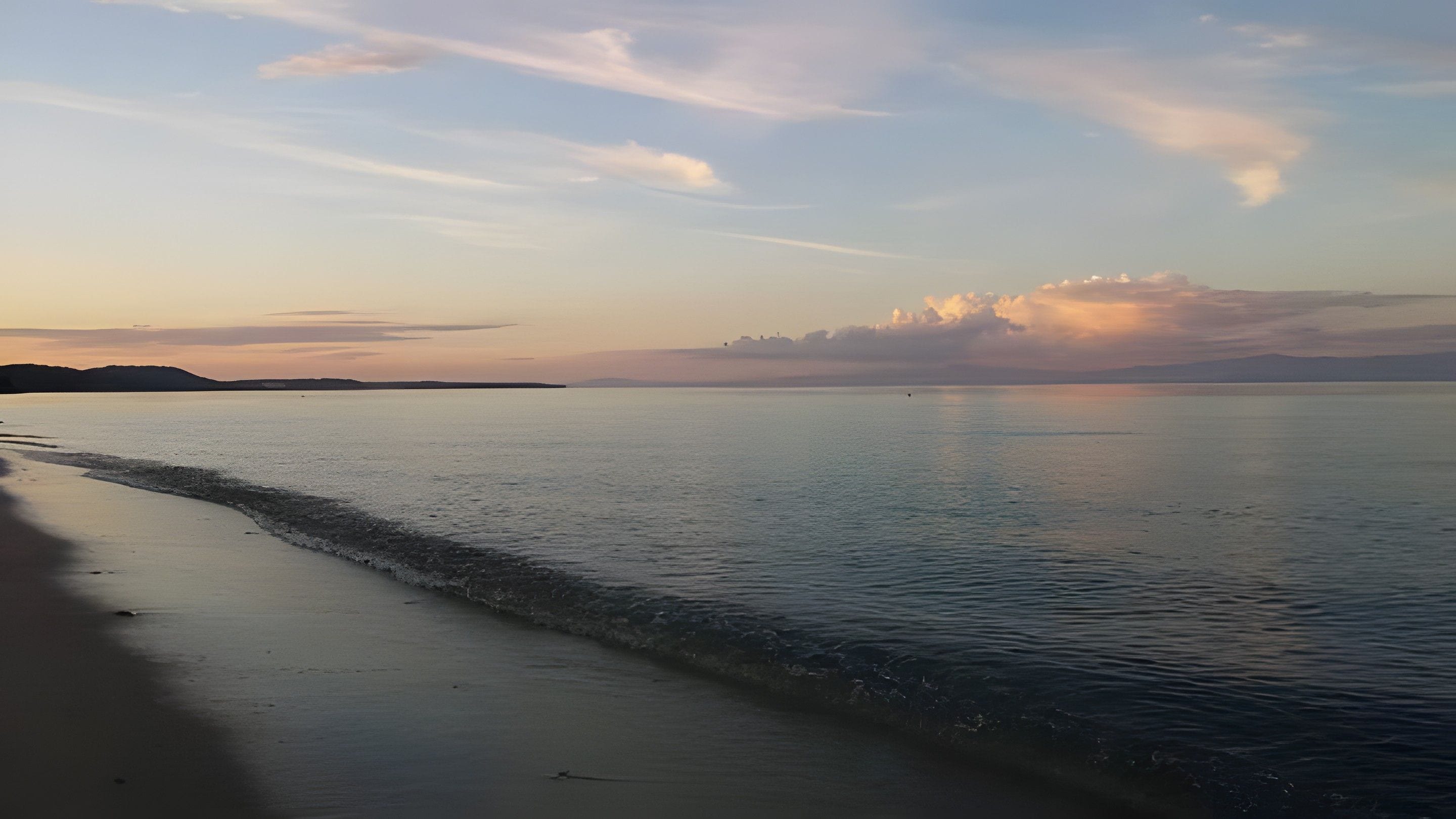 A beach with calm waters and a clear sky.