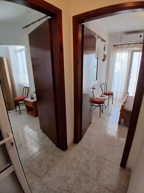 Una habitación con puerta de madera, una mesa de comedor con sillas y una ventana con persianas.