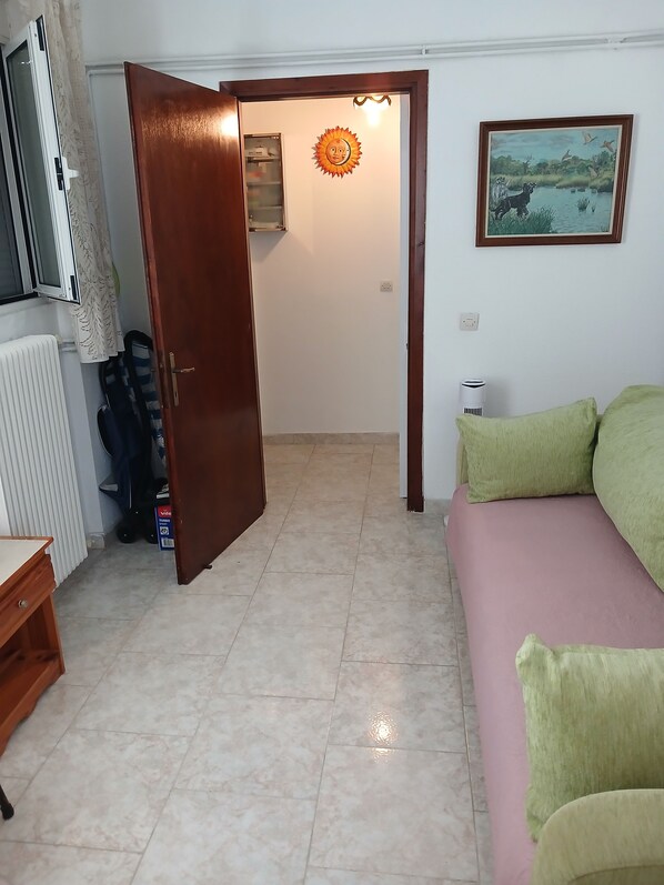 Una habitación con una cama, un radiador, un televisor y una puerta que da a otra habitación.