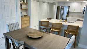 Una cocina moderna con una isla central, sillas de madera y una mesa de comedor.