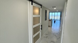 A hallway with a sliding door, a view to a balcony, and a tiled floor. - 204 Martinique in Ponce Inlet, FL (Ponce Inlet)
