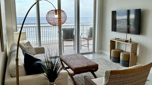A living room with a view of the ocean, a television, and a wicker coffee table. - 204 Martinique in Ponce Inlet, FL (Ponce Inlet)