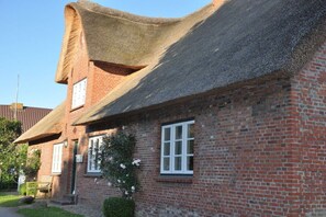A traditional brick house with a thatched roof and a small garden. - Old registry office studio apartment (Oldsum)