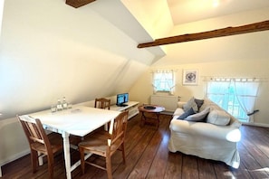 A cozy loft-style room with a dining table, chairs, a sofa, and a TV. - Old registry office studio apartment (Oldsum)