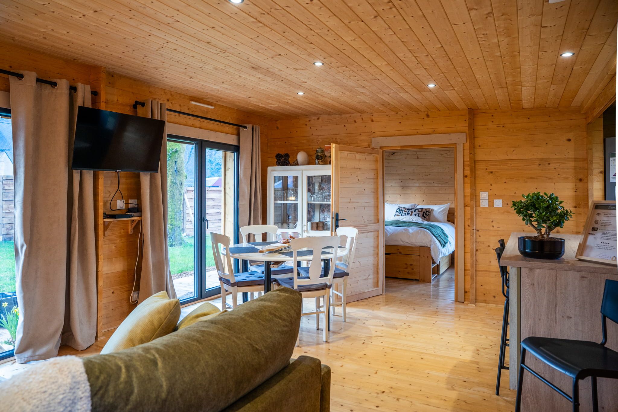 L'intérieur d'un chalet en bois comprend un coin repas, un canapé et un téléviseur.