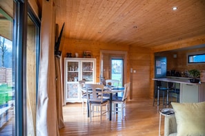 Interior de madera con comedor, cocina y ventanas amplias.