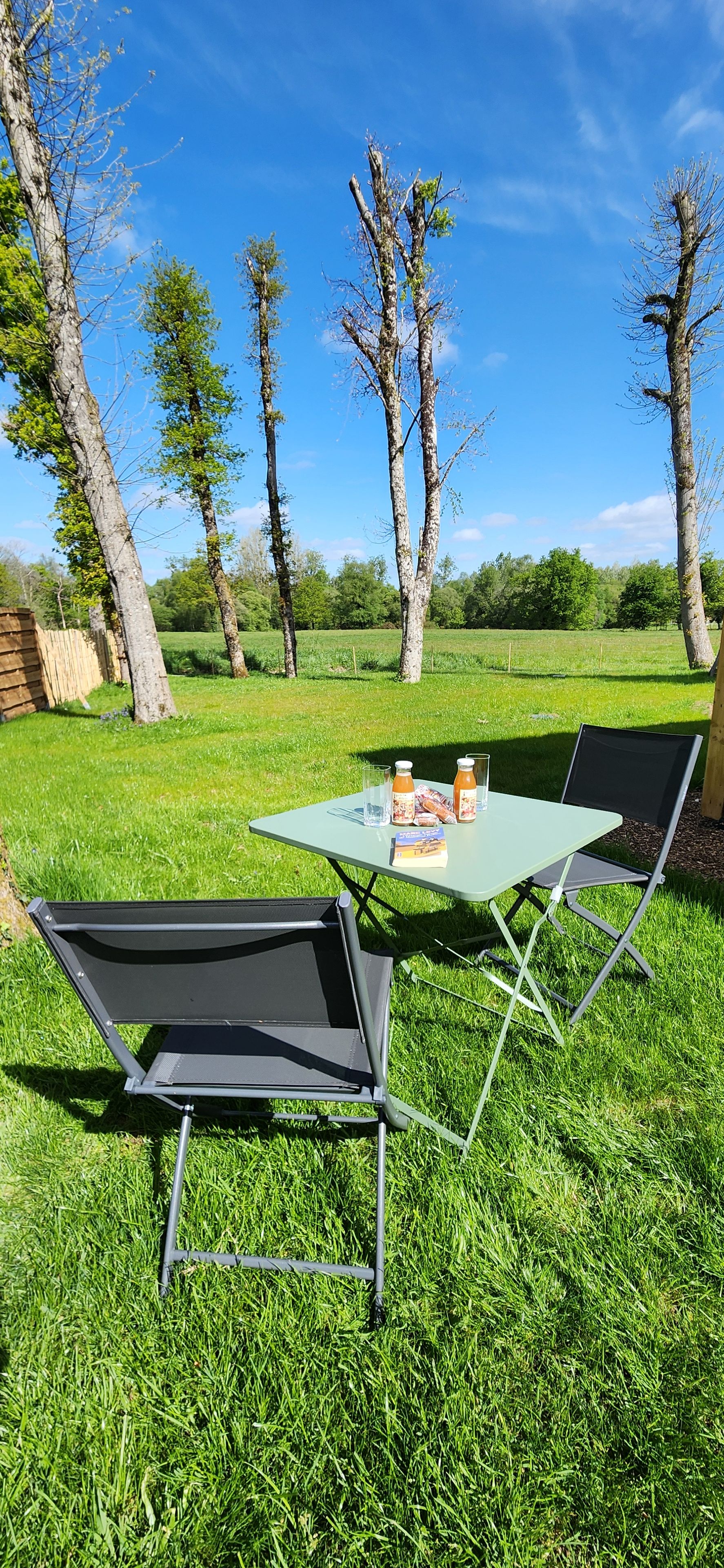 An outdoor seating area with a table and chairs, a bottle of water, and a glass of juice.