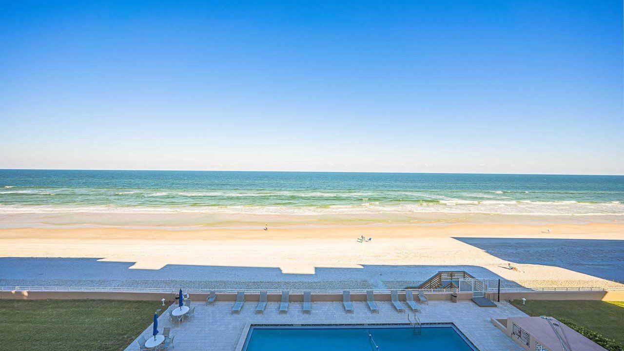 A pool area with a view of the beach and ocean.