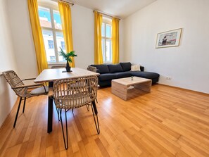 A modern living space with a dining table, chairs, a sofa, a coffee table, and a potted plant. - Stay Longer in Vienna 2BR near Stadthalle (Vienna)