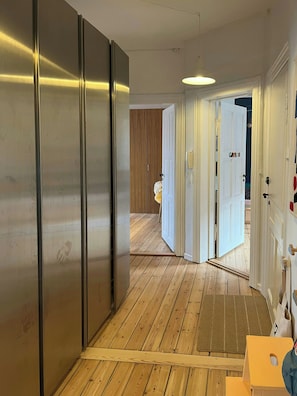 A hallway with wooden flooring, a white door, and a metal structure on the left. - Light and spacious flat in Nørrebro with garden (København)