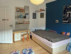 A bedroom with a bed, a desk, a chair, and a shelf with various items. - Light and spacious flat in Nørrebro with garden (København)