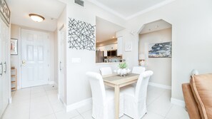 Un comedor con mesa de madera, sillas blancas y un centro decorativo.