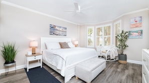 A bedroom with a bed, bedside tables, a nightstand, a chair, a dresser, a plant, and a ceiling fan. - 2206 Harbour Village (Ponce Inlet)