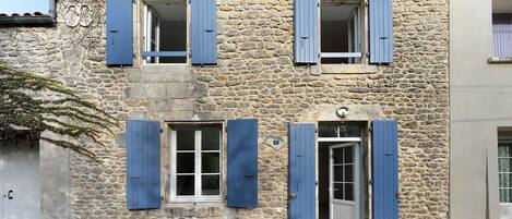 A stone building with multiple windows and shutters, featuring a traditional architectural style.