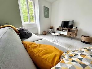 Una sala de estar moderna con un sofá, una mesa de centro, un televisor y una estantería.