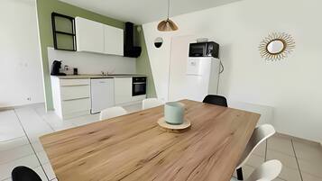 Eine moderne Küche mit weißen Schränken, einem Holztisch und einer Mikrowelle.