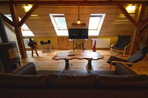Een gezellig zolderkamertje met een houten vloer, een bank, een tafel en een televisie.
