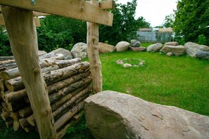 A rustic wooden structure with logs and rocks, set in a grassy outdoor area. - Holiday apartment with 1 bedroom (Rockow)