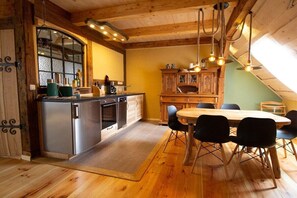 Een moderne keuken met roestvrijstalen apparatuur, een eethoek met een houten tafel en stoelen, en uitzicht op het omliggende landschap.