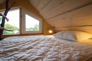 A bedroom with a bed, a window, and a wooden ceiling. - Holiday apartment with 1 bedroom (Rockow)
