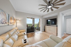 Een moderne woonkamer met een bank, een televisie en een plafondventilator.