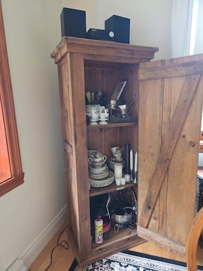 A wooden cabinet with shelves containing kitchenware and a small speaker. - Country house with rustic charm. Tastefully decorated. Photos available upon request (Saint-Sauveur)