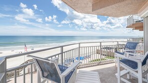 A balcony with a view of a beach, lounge chairs, and a flag. - #305 Blue Surf 2/2 Oceanfront Traffic Free Beach (Daytona Beach Shores)