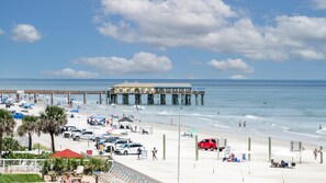 Une plage avec une jetée, des parasols et des chaises de plage.