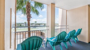 A balcony with a view of a tennis court, palm trees, and a clear sky. - #305 Blue Surf 2/2 Oceanfront Traffic Free Beach (Daytona Beach Shores)