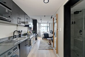 Ett modernt kök med diskmaskin, diskho och en bänkskiva med ett diskställ.