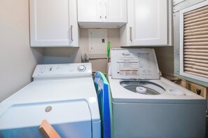 A laundry room with a front-loading washer and dryer, a green bottle, and a Whirlpool instruction manual on the dryer. - #305 Sandcastle Oceanfront 3/2 Traffic Free Beach Ponce Inlet (Ponce Inlet)