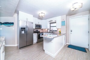 A modern kitchen with white cabinetry, stainless steel appliances, and a granite countertop. - #305 Sandcastle Oceanfront 3/2 Traffic Free Beach Ponce Inlet (Ponce Inlet)