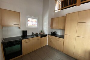 A kitchen with light wooden cabinets, a black countertop, and a window with a view. - Panoramic View - Gallery (Tschiertschen)
