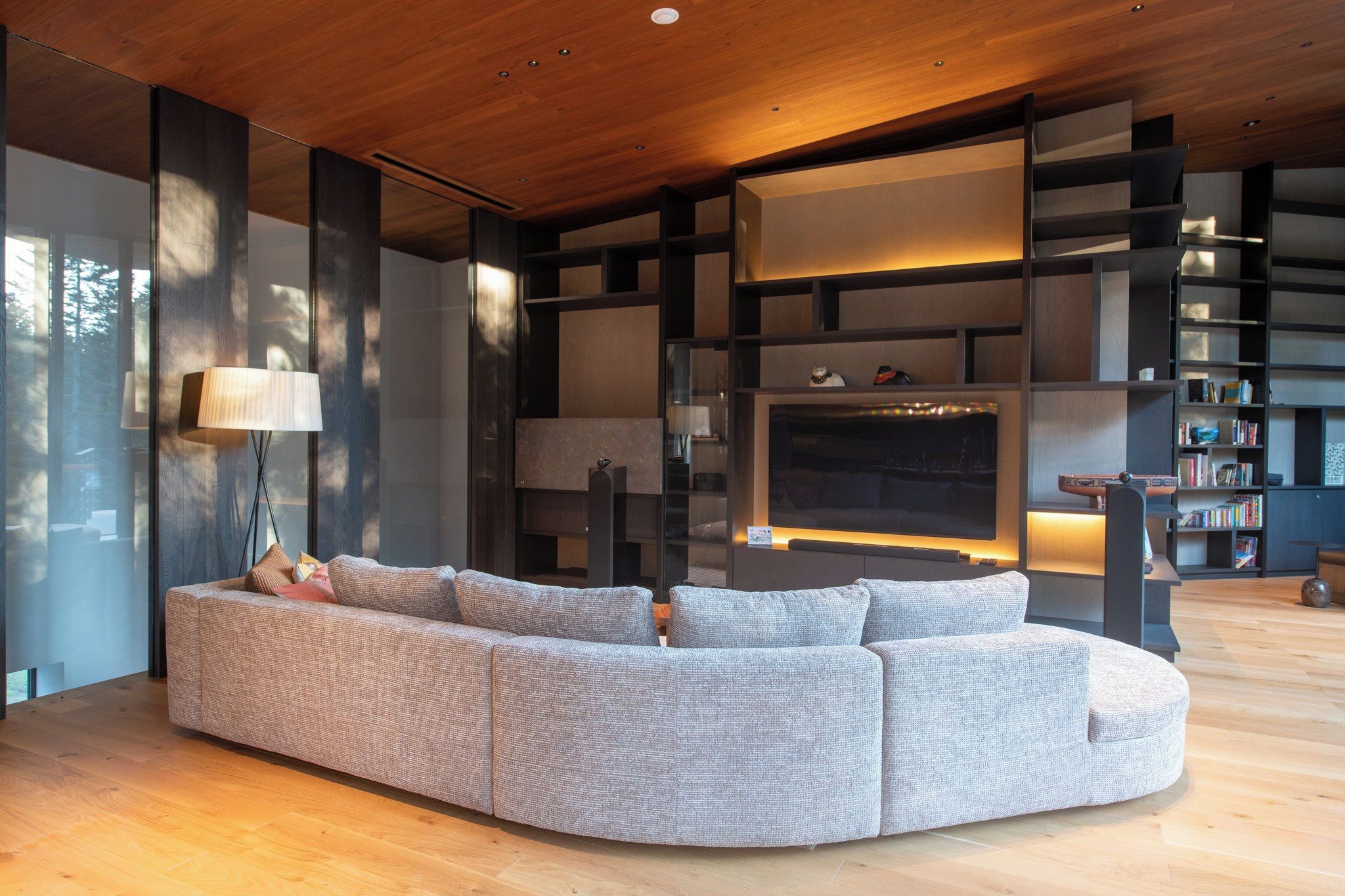 Una sala moderna con un sofá modular, una chimenea y estanterías empotradas.
