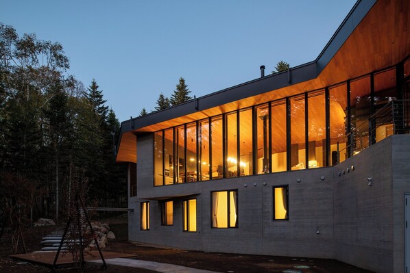 A modern building with large windows, a concrete facade, and a wooden sloped roof.