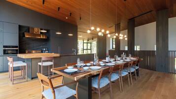 Cozinha moderna com ilha central, área de jantar com mesa comprida posta para seis pessoas, e uma janela grande que oferece luz natural.