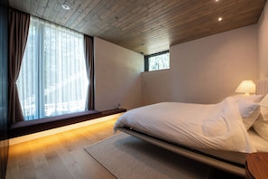 Quarto moderno com cama, mesa de cabeceira e janela com cortinas.