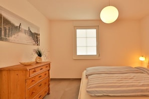 Ein Schlafzimmer mit einem Bett, einem Schminktisch, einem Fenster und einem Wandbild.