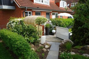 Ein Wohngarten mit einem Weg, einem weißen Zaun und einem Haus mit rotem Dach.
