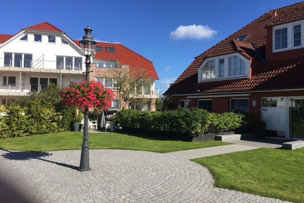 A residential area with houses, a cobblestone path, and a street lamp.