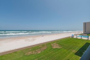 Blick auf einen Strand mit Pool und Liegestühlen.