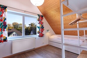 A room with a bunk bed, a window with curtains, a radiator, and a ceiling light. - House by the dike, mill, 1st floor, 60m² (Prerow)