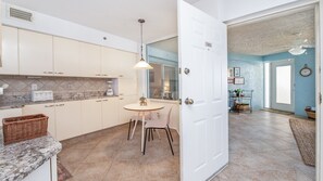 A kitchen with white cabinets, a dining table with chairs, a blender, and a wicker basket on the counter. - 3202 Towers in Ponce Inlet, FL (Ponce Inlet)