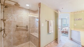 A modern bathroom with a glass shower enclosure, a towel rack, and a visible bedroom door. - 3202 Towers in Ponce Inlet, FL (Ponce Inlet)
