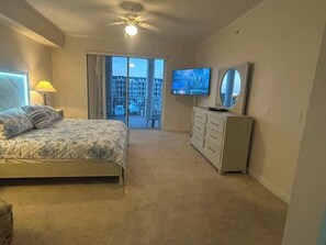 A bedroom with a bed, a dresser, a television, and a balcony with a view. - 3307 Harbor Village in Ponce Inlet, FL (Ponce Inlet)
