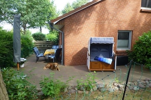A brick house with a patio, a covered seating area, and a dog lying on the ground. - Dike butterfly Boltenhagen (Ostseebad Boltenhagen)